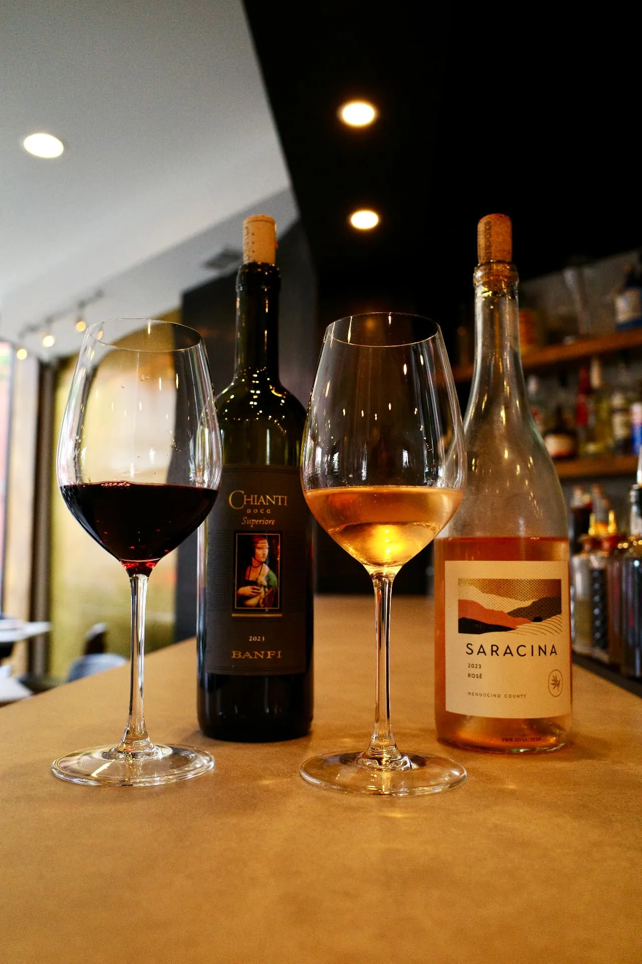 Glasses of red and rosé wine beside bottles at the Five Corners bar
