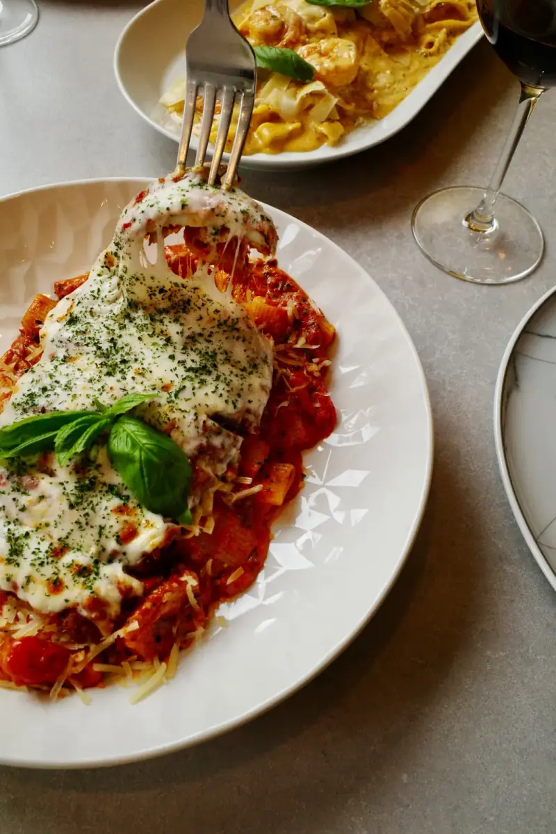 Chicken parmigiana with melted cheese and pasta at Five Corners Ristorante